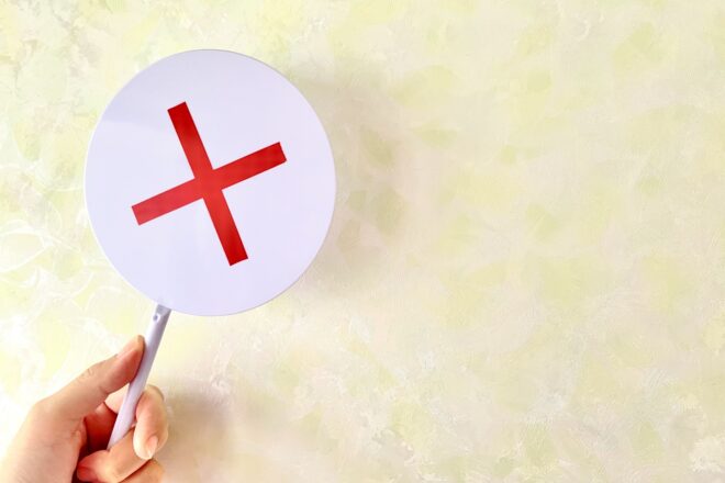 ×マークを持つ手